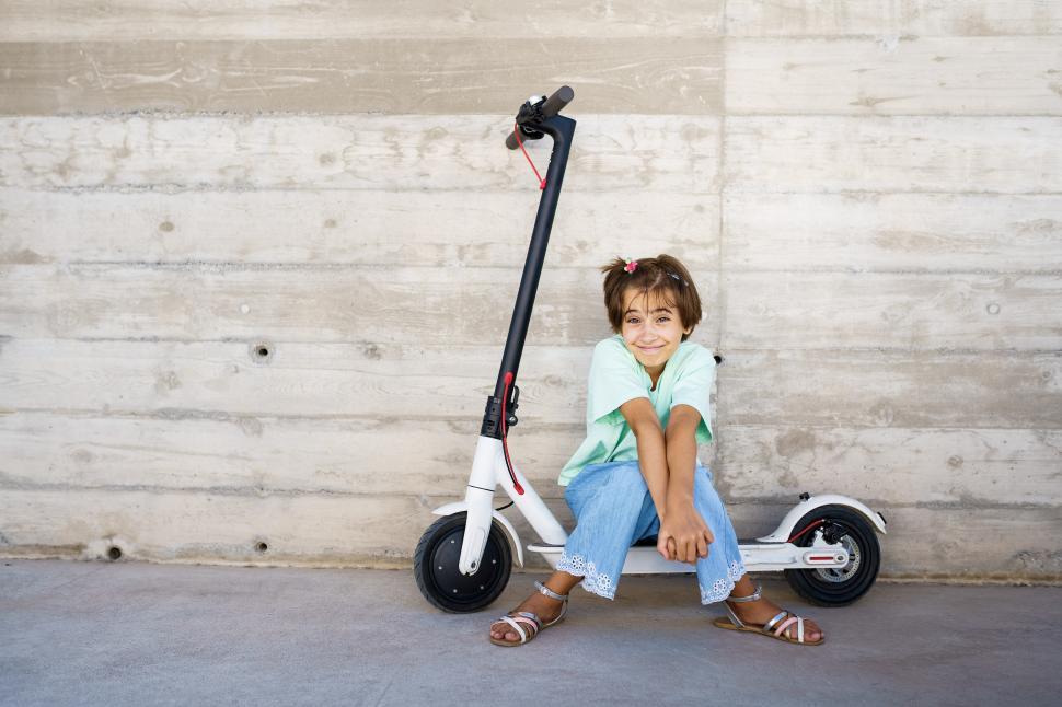 Free Image of Little girl sitting on an electric scooter in the street 