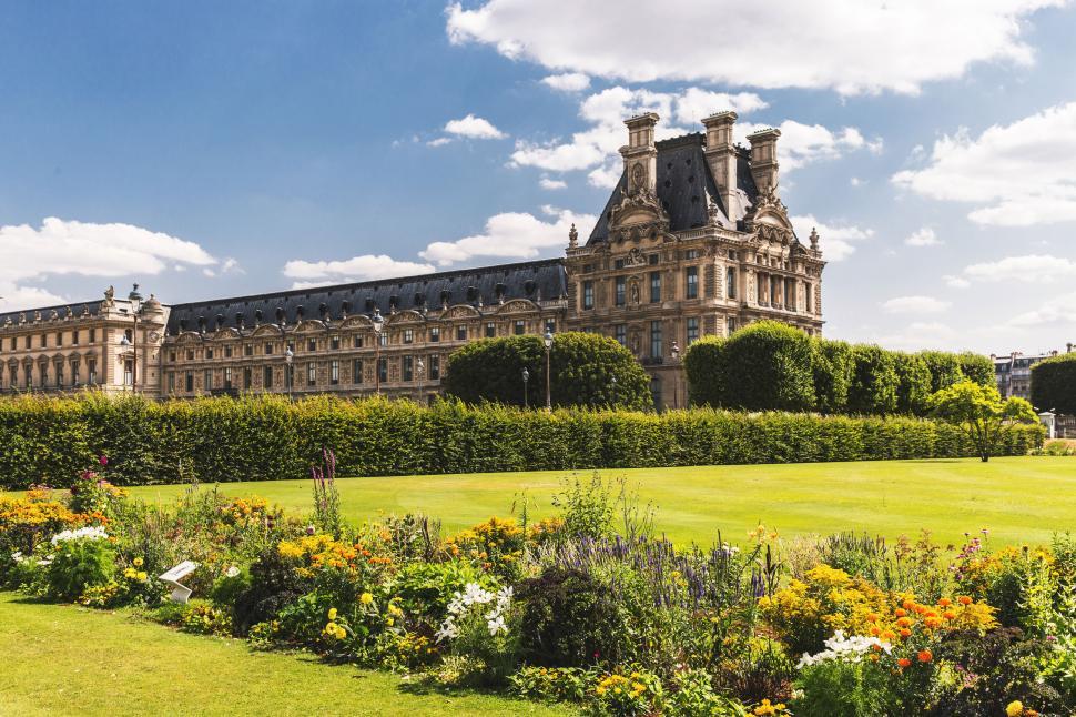 Free Image of A large old building with a lawn and bushes with tuileries garden in the background 