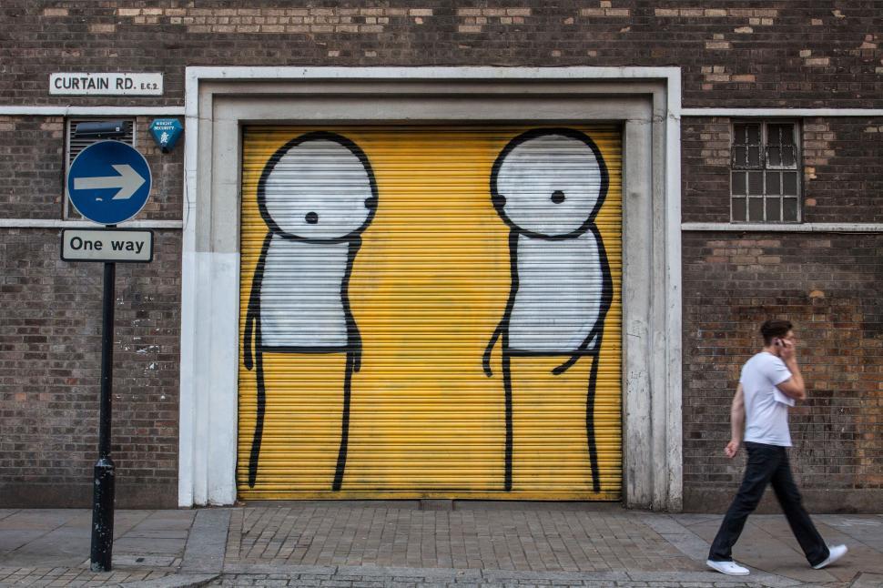 Free Image of A man walking past a yellow door with two cartoon characters 