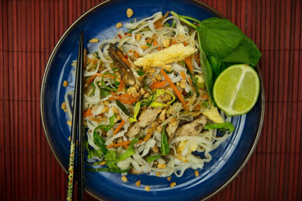 Free Image of A plate of food with chopsticks and a lime 