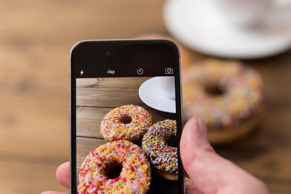 Free Image of A hand holding a phone with a phone and a picture of donuts 