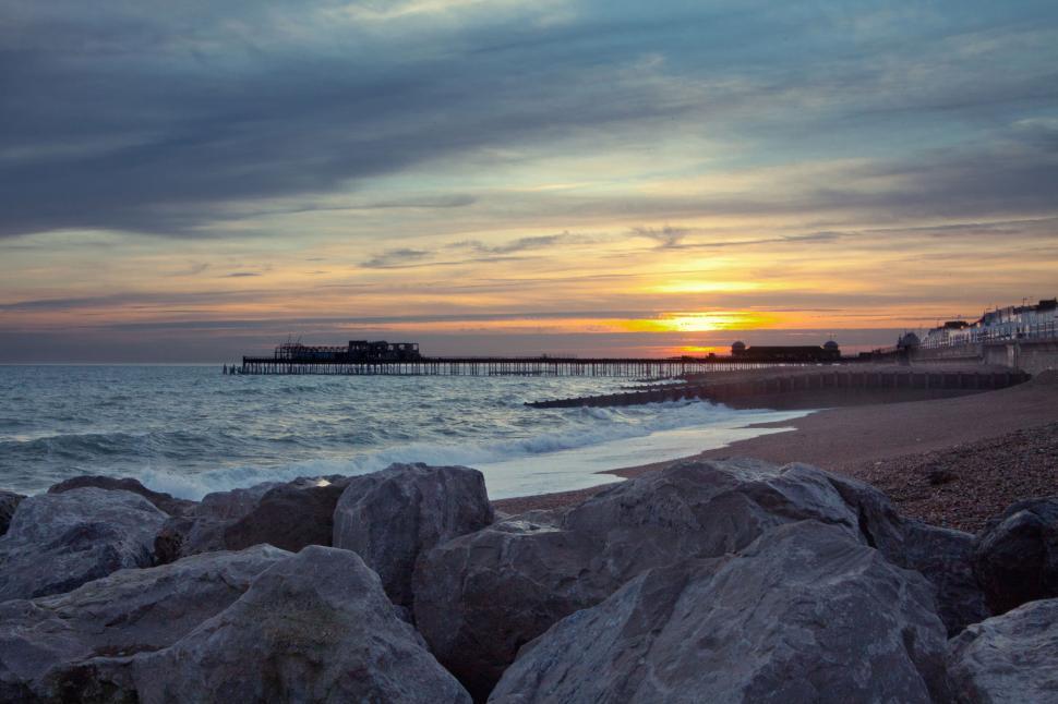 Free Image of A beach with rocks and a pier 