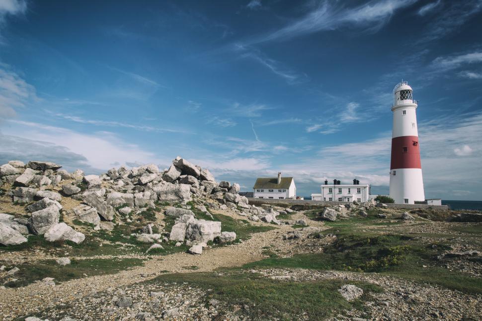 Free Image of A lighthouse with rocks and a building 