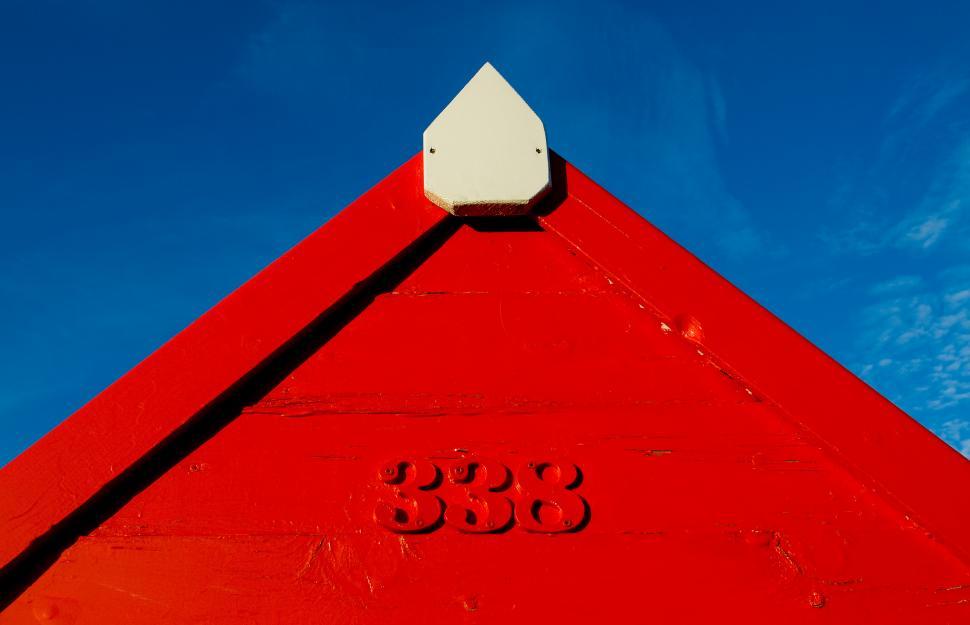 Free Image of A red triangular building with numbers and a white triangle 