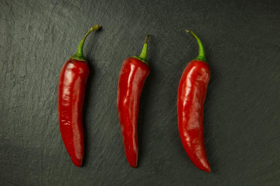 Free Image of A group of red peppers on a black surface 