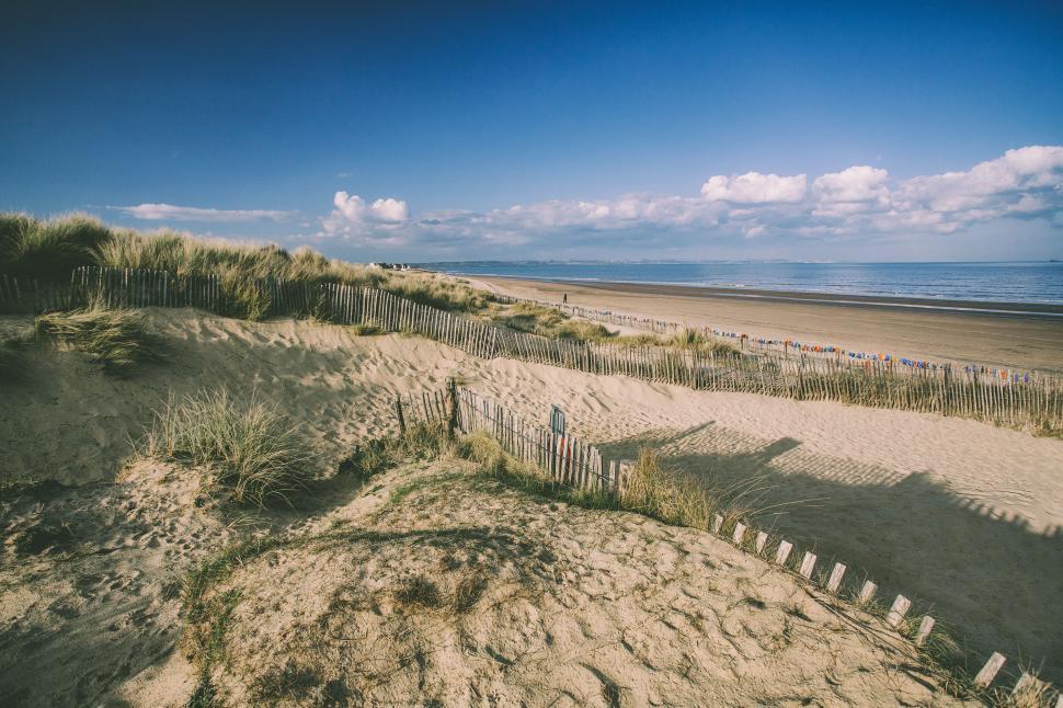 Free Image of A sandy beach with a fence and grass 