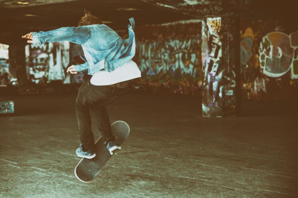 Free Image of Skater dong tricks, graffiti in the background 