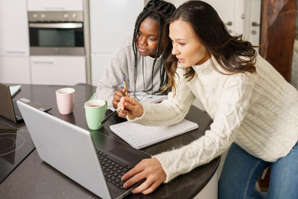 Free Image of Two college girls studying together at home with laptops while drinking coffee 