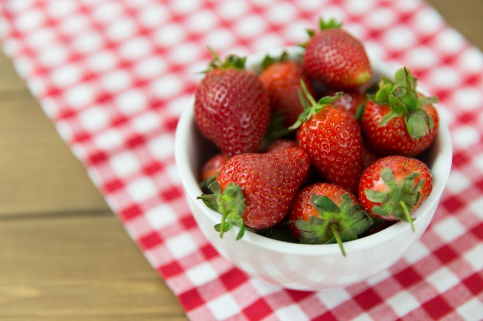 Free Image of A bowl of strawberries on a table with gingham tablecloth 