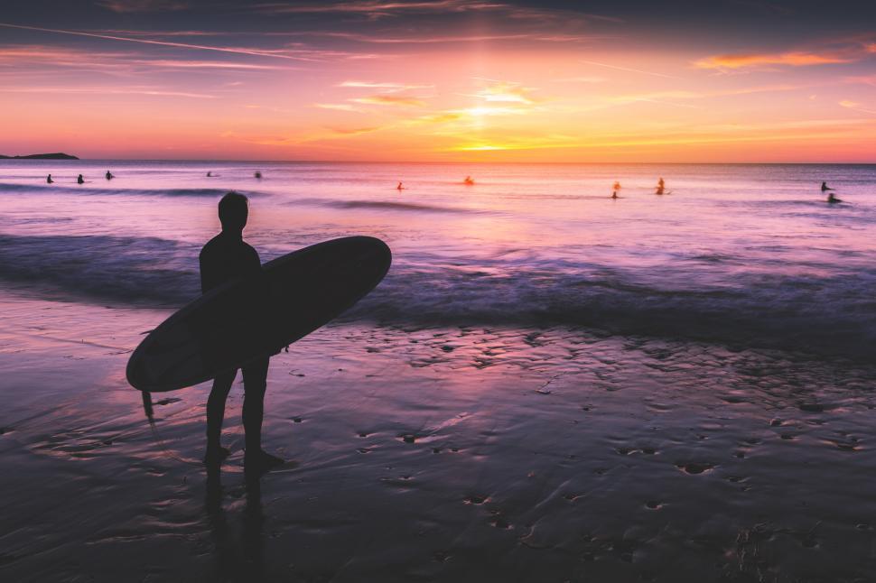 Free Image of A man holding a surfboard on a beach 