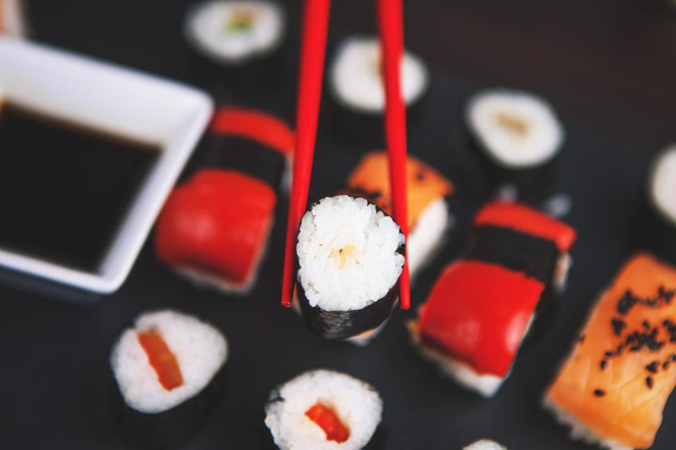 Free Image of Chopsticks holding sushi on a plate 