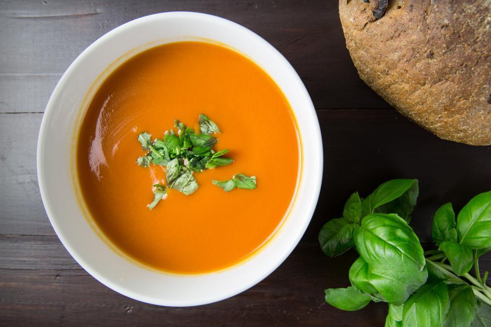 Free Image of A bowl of soup next to a loaf of bread 