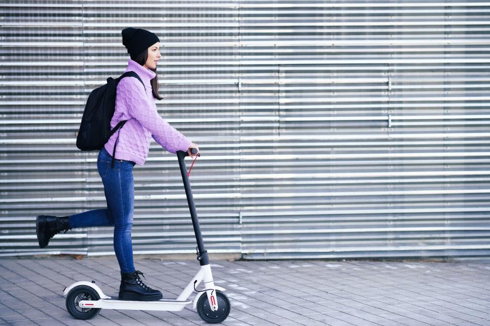 Free Image of Young woman in her twenties riding an electric scooter. 