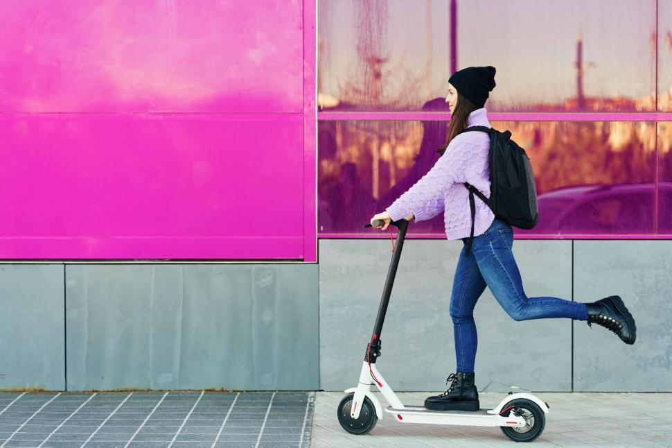 Free Image of Young woman in her twenties riding an electric scooter. 