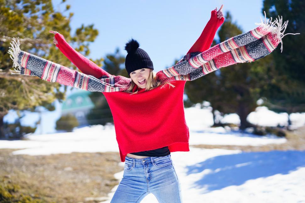 Free Image of Happy young blonde woman waving her scarf in the wind in a forest in the snowy mountains. 