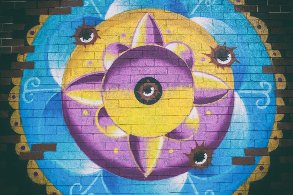 Free Image of A colorful painted wall with eyes and a flower 