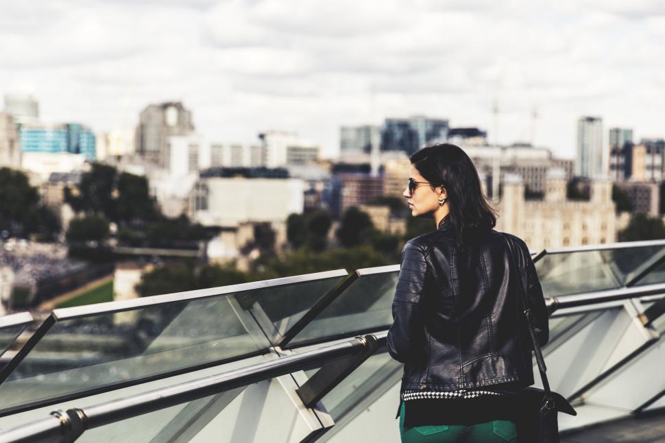 Free Image of A woman standing on a bridge looking at a city 