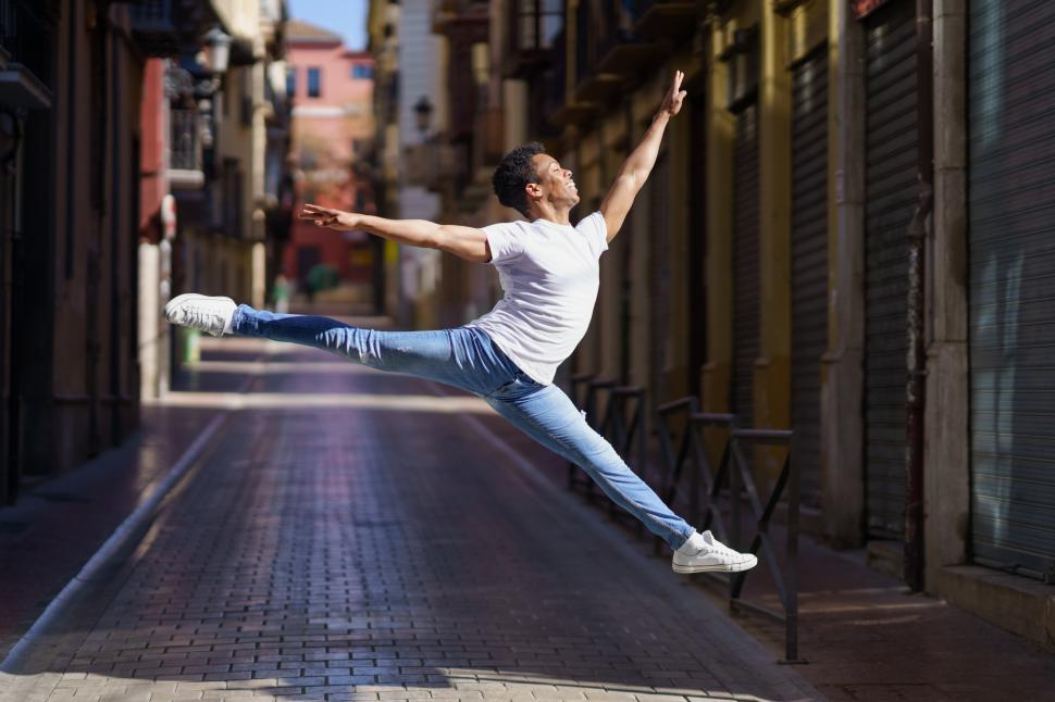 Free Image of Black athletic man doing an acrobatic jump outdoors 