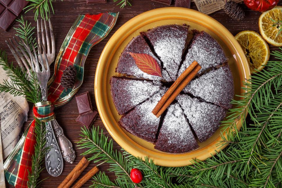 Free Image of A plate of chocolate cake with a cinnamon stick and pine branches 