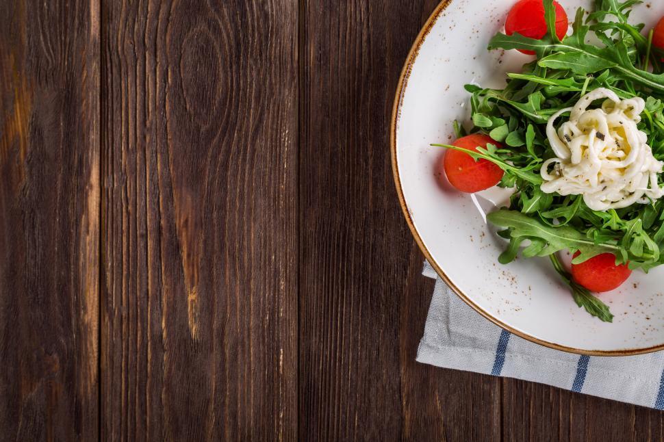 Free Image of A plate of salad on a wood table 