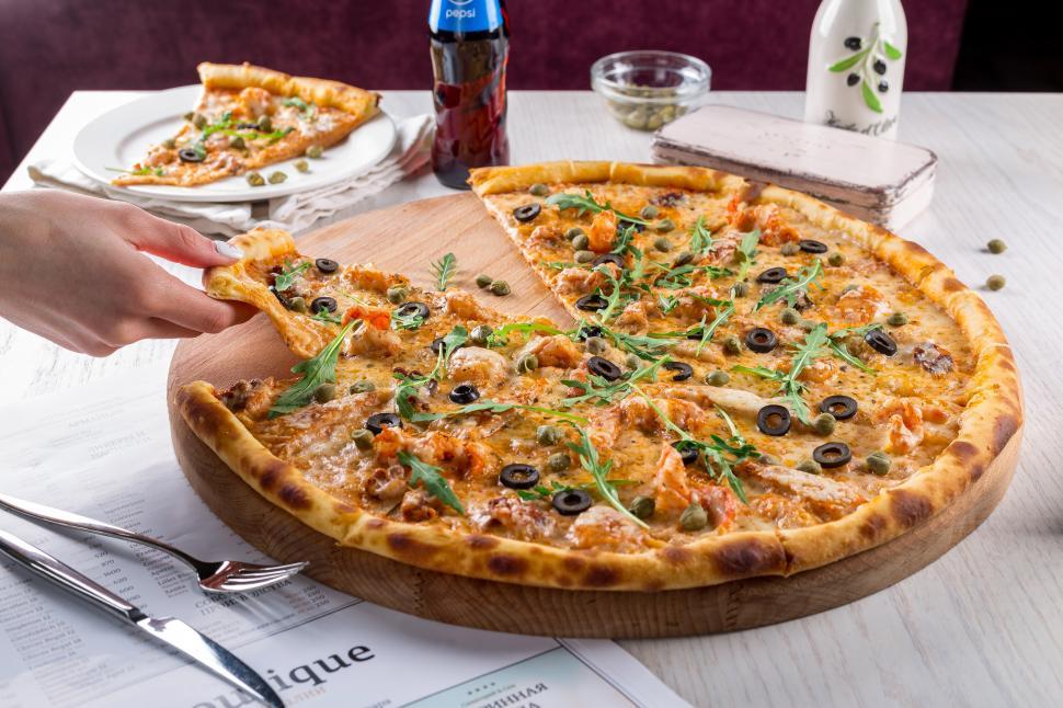 Free Image of A pizza with olives and cheese on a wooden plate 