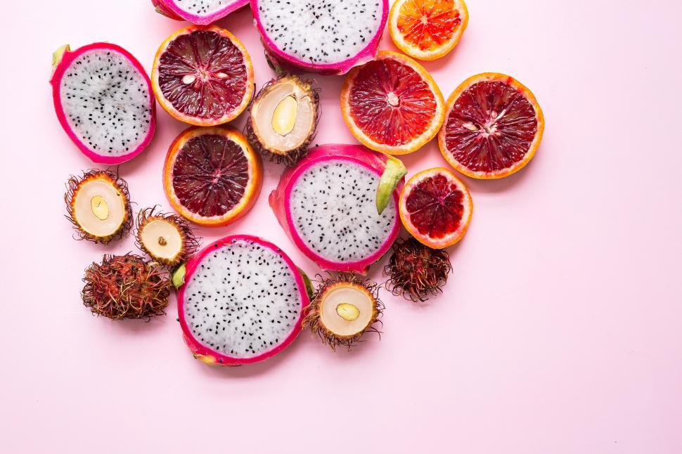 Free Image of A group of cut fruit on a pink background 