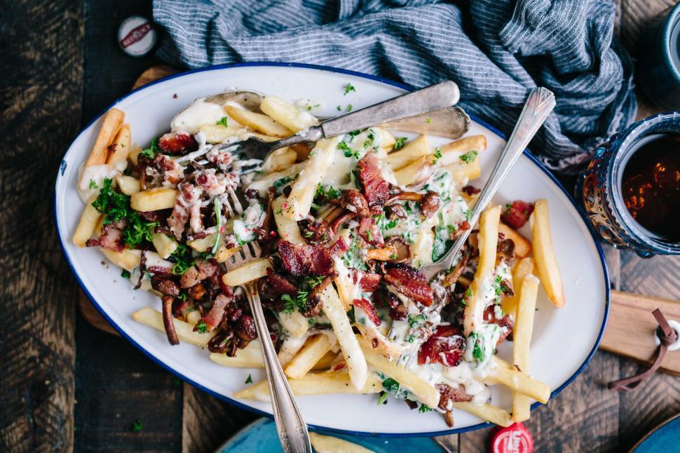 Free Image of A plate of french fries with bacon and sauce 