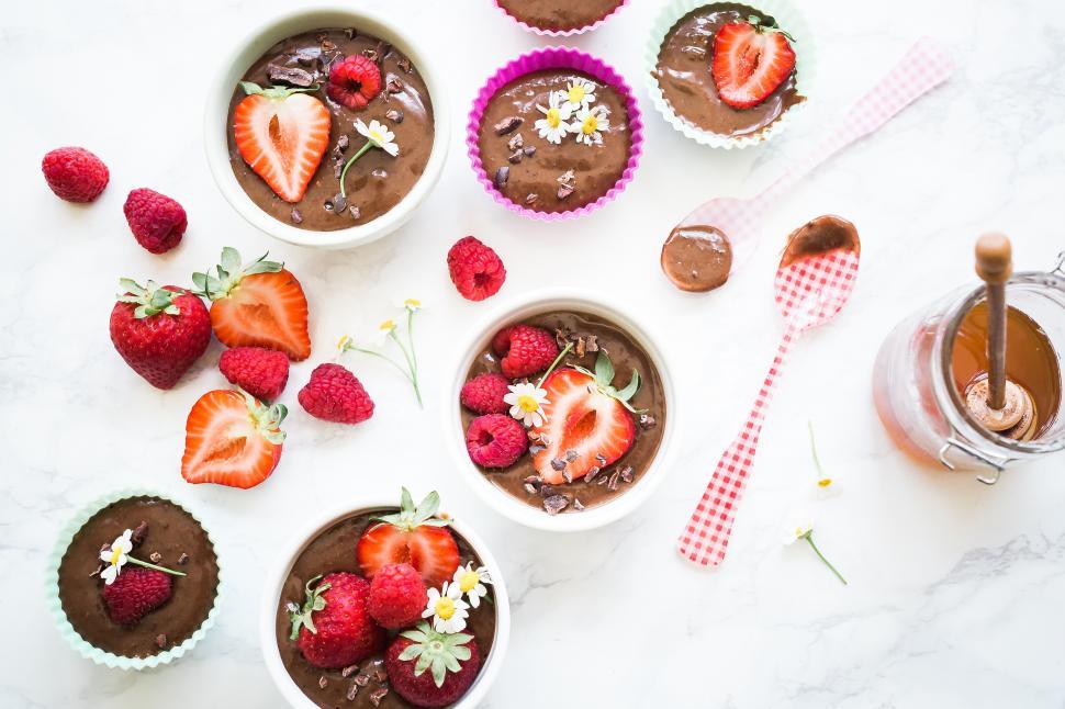 Free Image of A group of cups of chocolate pudding with strawberries and flowers 