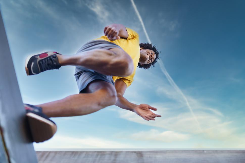 Free Image of View from below of black man jumping on his run. 