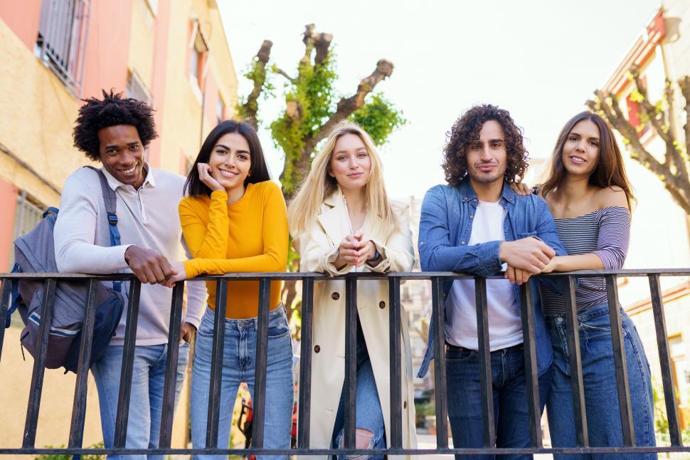 Free Image of Multi-ethnic group of friends gathered in the street leaning on a railing. 