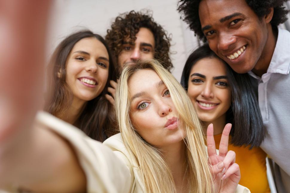 Free Image of Multi-ethnic group of friends taking a selfie together while having fun outdoors. 