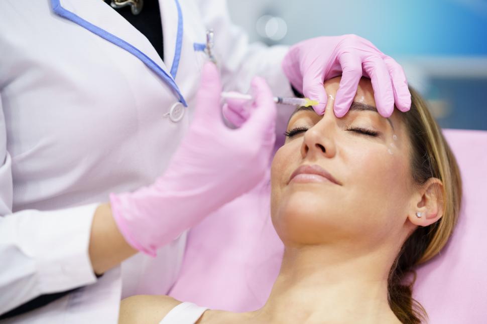 Free Image of Aesthetic doctor injecting botulinum toxin into the forehead of her middle-aged patient. 