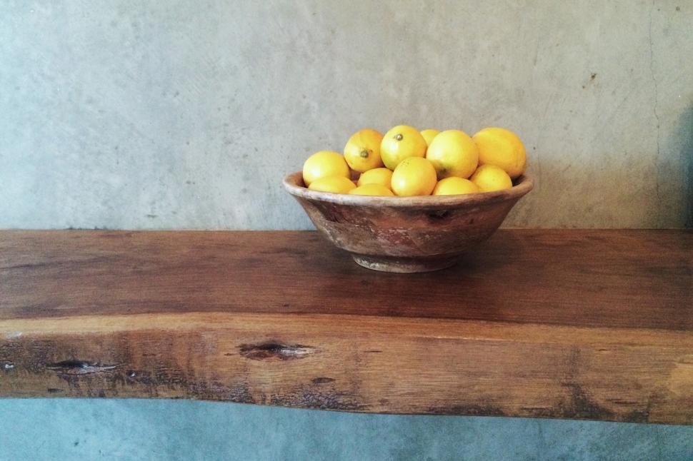 Free Image of A bowl of lemons on a wooden shelf 