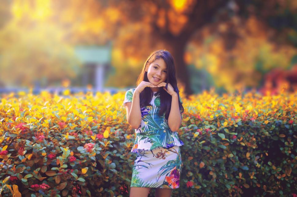 Free Image of A girl standing in front of a bush 