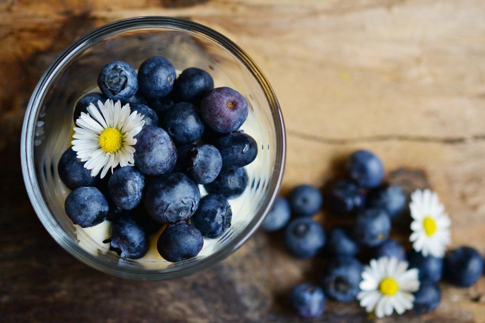 Free Image of A glass of blueberries and a flower 
