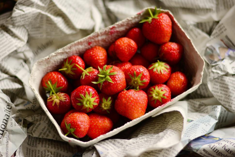Free Image of A container of strawberries on a newspaper 