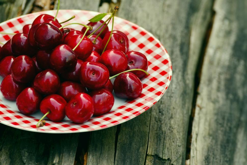 Free Image of A plate of cherries on a wood surface 