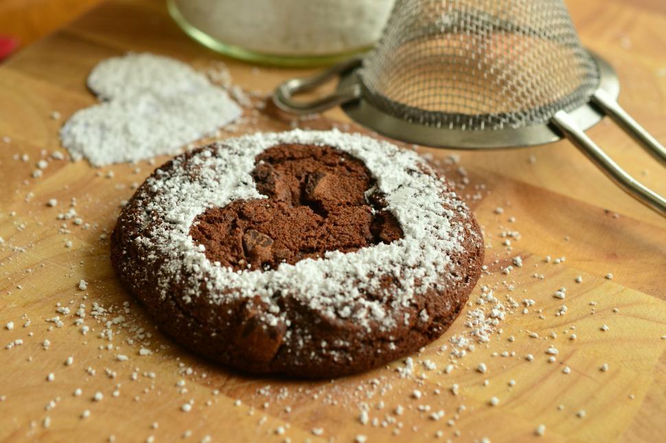 Free Image of A cookie with powdered sugar on a wooden surface 