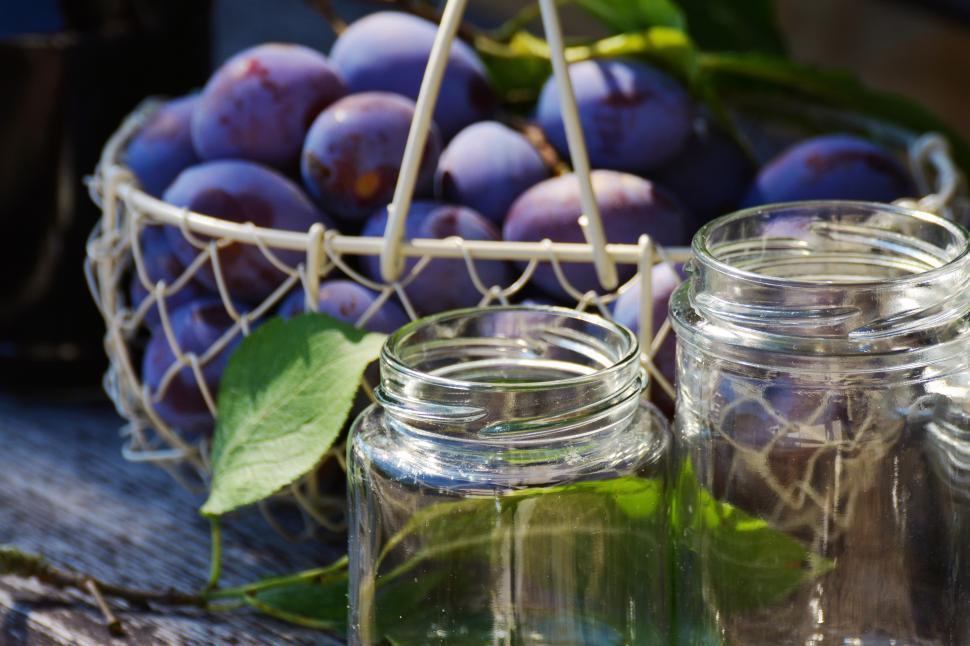 Free Image of A basket of plums and jars 
