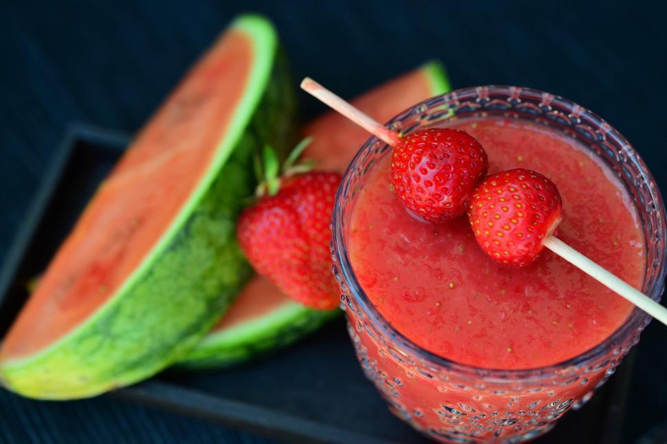 Free Image of A glass of strawberry smoothie with strawberries on top 