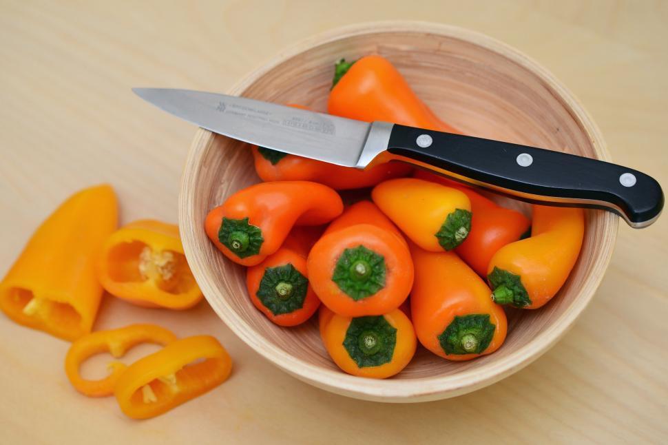 Free Image of A bowl of orange peppers and a knife 
