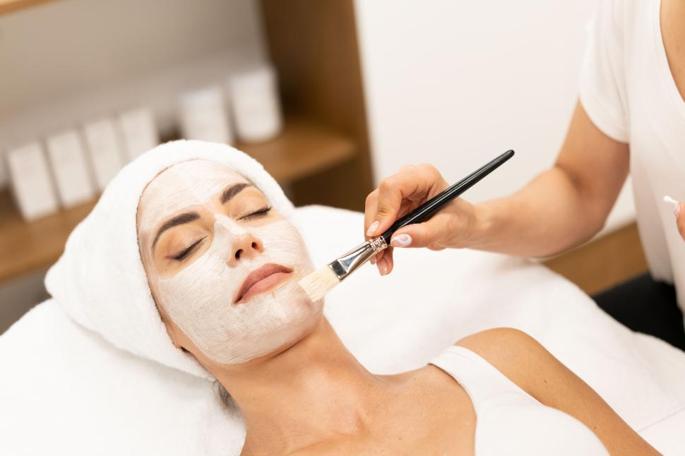 Free Image of Aesthetics applying a mask to the face of a Middle-aged woman in modern wellness center. 