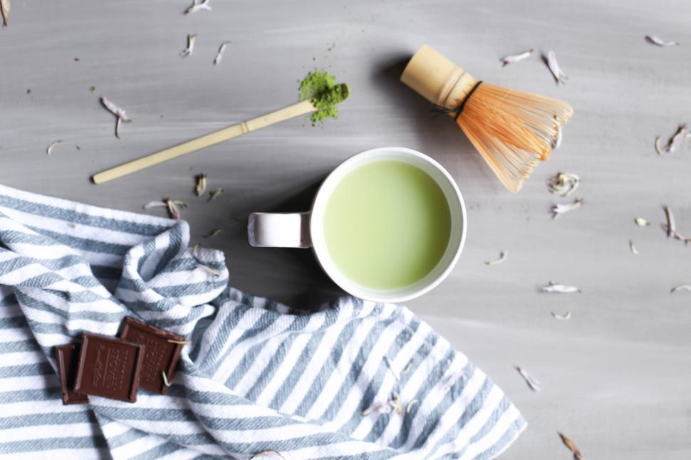 Free Image of A cup of green tea with a whisk and chocolate bars 