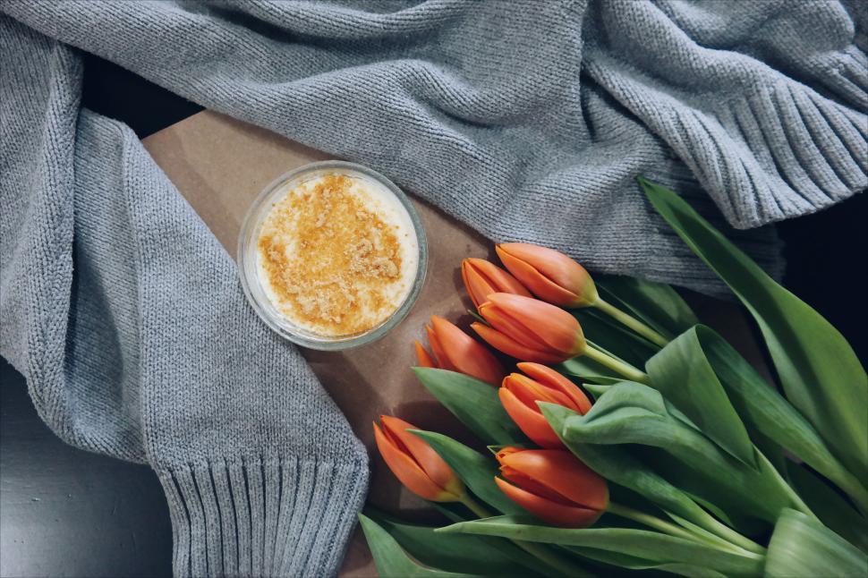 Free Image of A bouquet of orange tulips next to a glass of liquid 