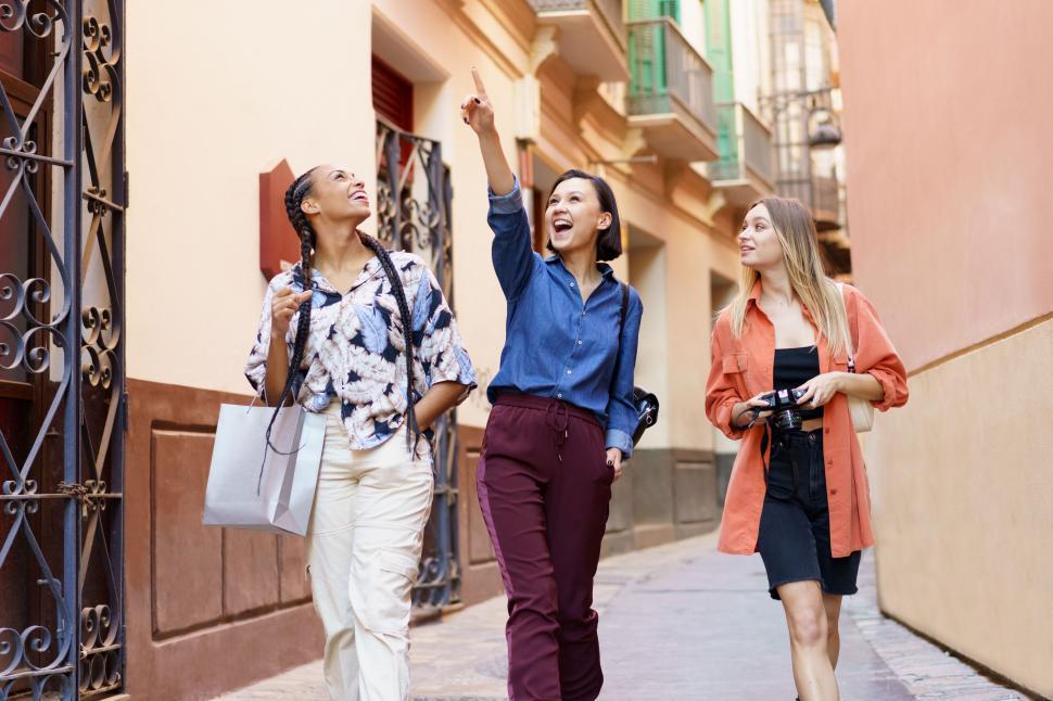 Free Image of Delightful multiracial ladies looking up against city building wall 