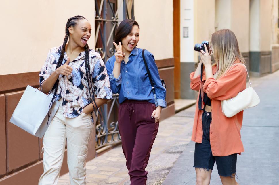 Free Image of Content lady taking photo of delighted female friends on street 