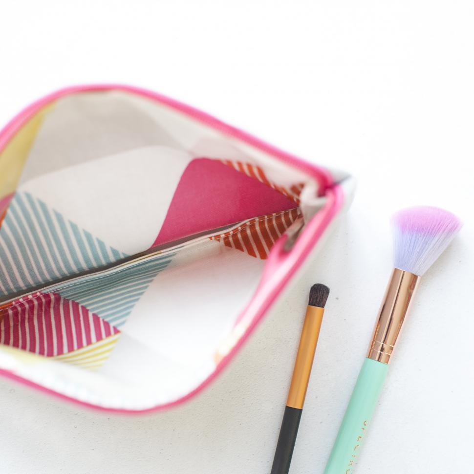 Free Image of A makeup brushes next to a pink and white bag 