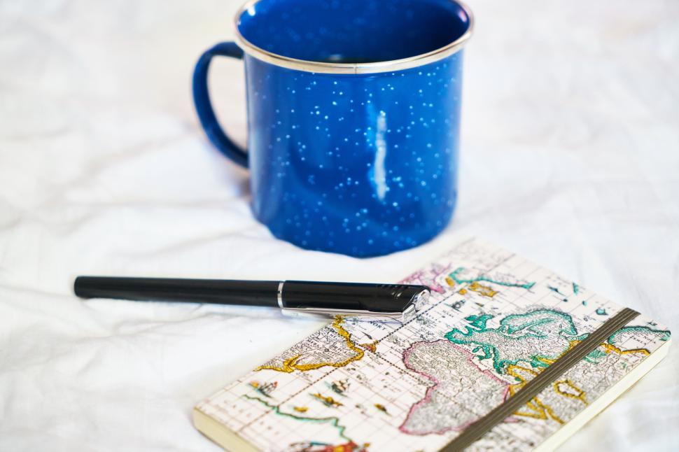Free Image of A blue mug and a pen on a notebook 