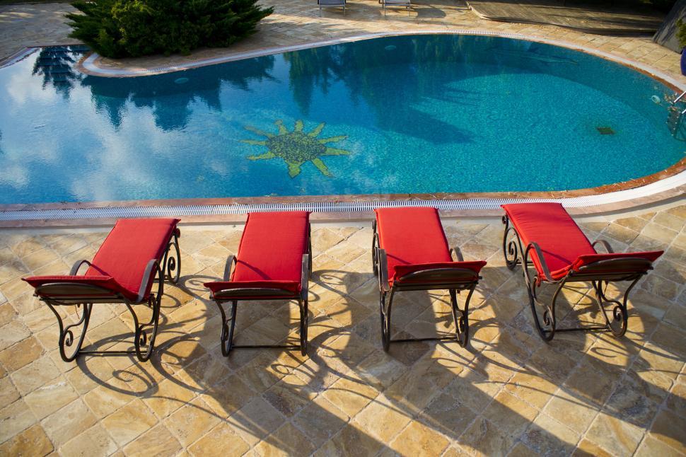 Free Image of A pool with chairs and a sun on the side 