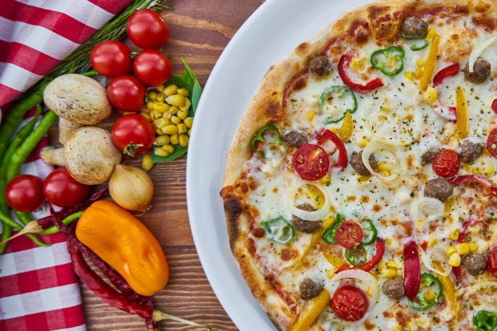 Free Image of A pizza on a plate next to vegetables 